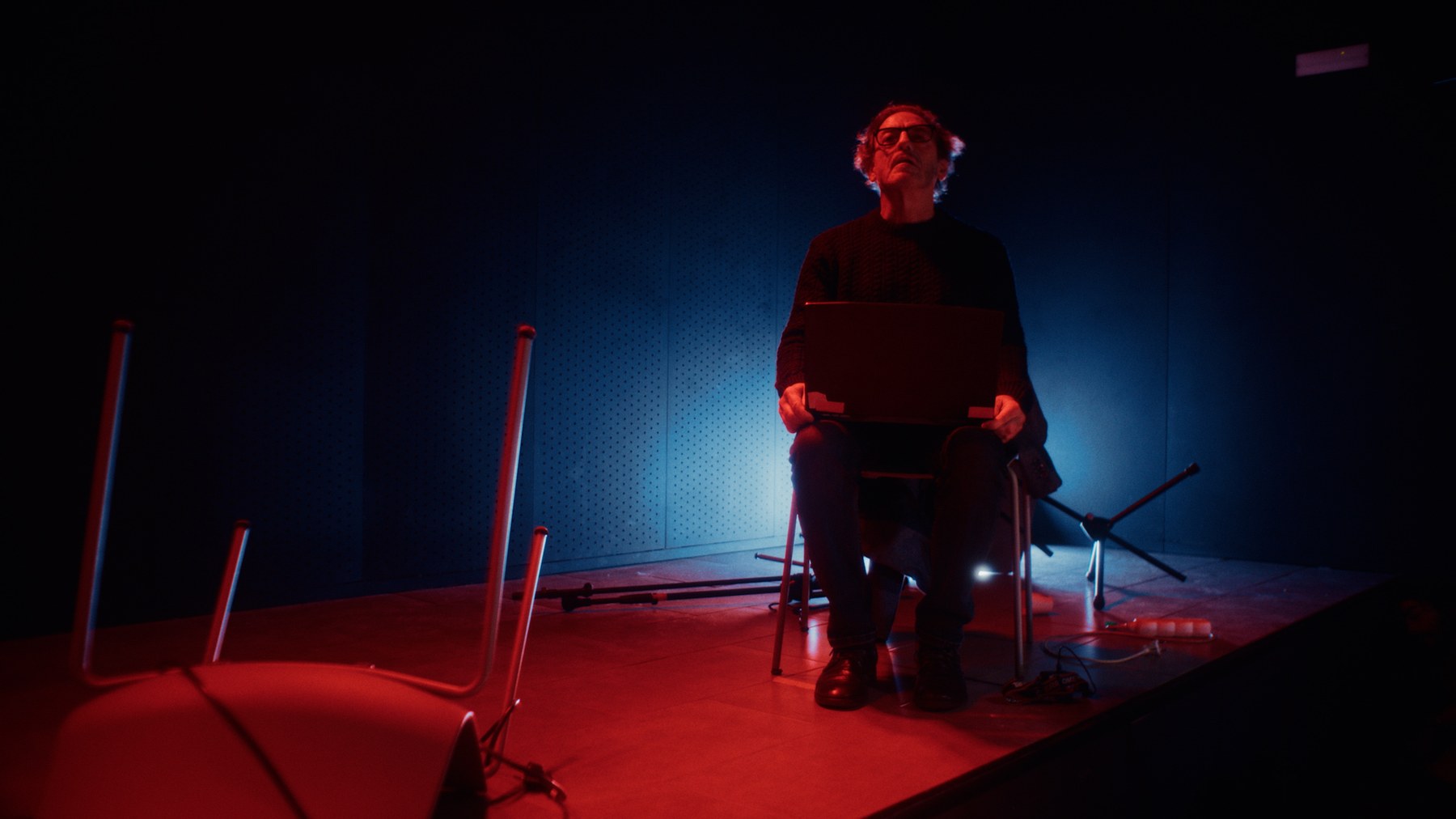 Personaje sentado bajo iluminación roja y azul